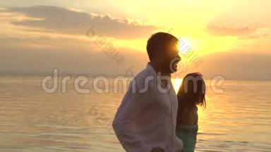 年轻的幸福夫妇在日落时在海滩上奔跑。 爱的概念。